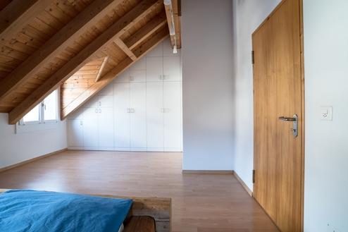 Nischenlösung für Einbauschrank an holzbelassener Dachschräge Nischenlösung für weißen Einbauschrank mit Schubladen und Türen an in dunklem Holz belassener Dachschräge